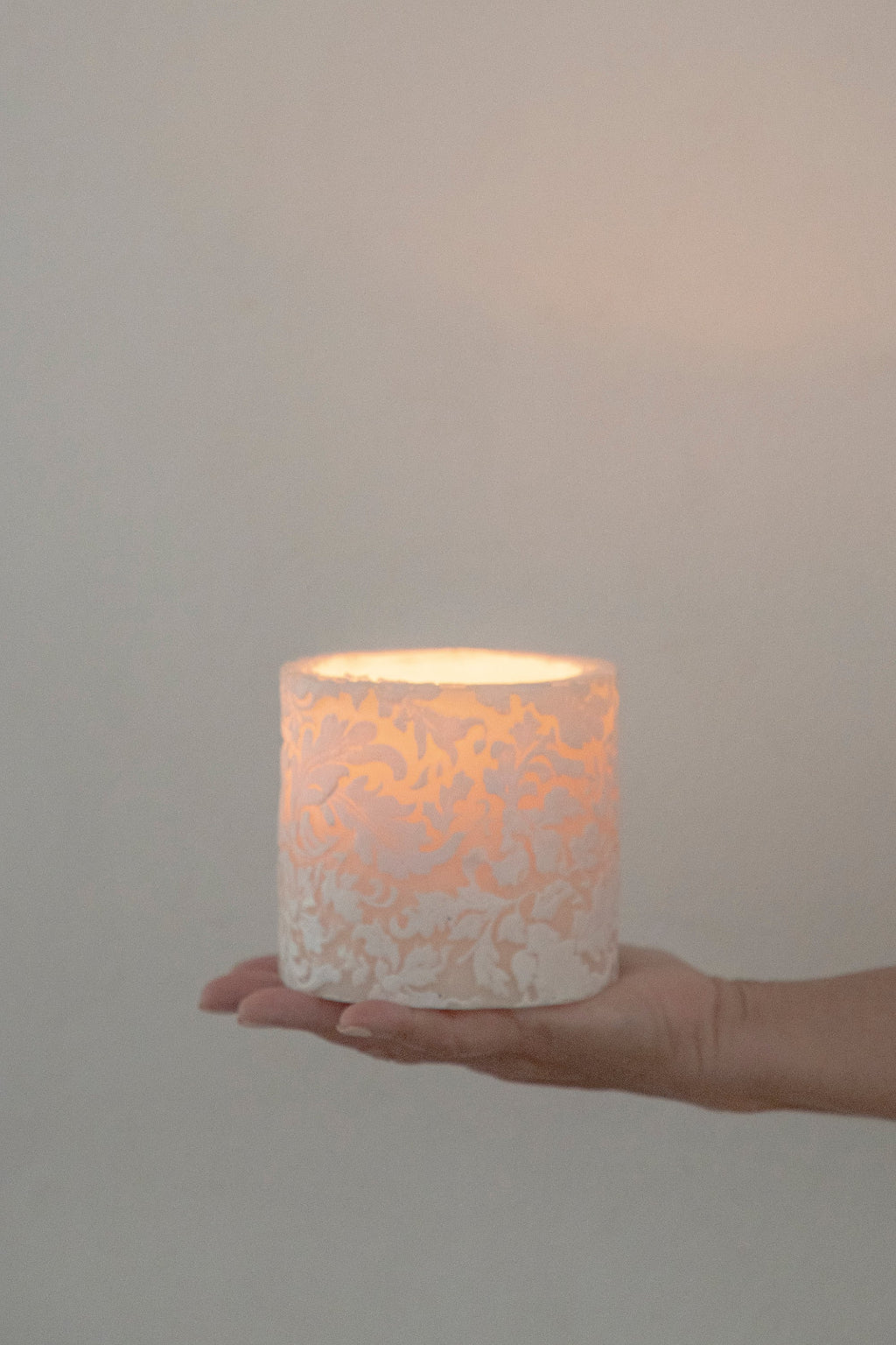 Hand holding a decorative candle with a textured surface